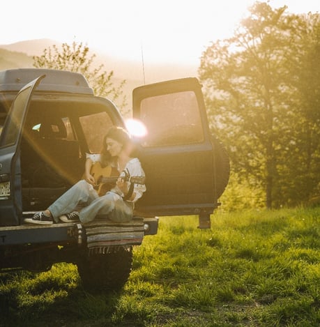 Jeune femme apprenant la guitare en vacance dans un van