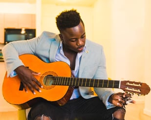 Homme assis avec une guitare qui apprendre la bonne posture pour jouer de la guitare