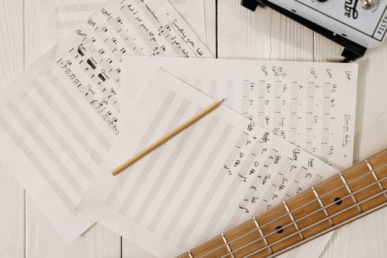 Une guitare posée sur une partition écrite à la main - Apprendre à lire la musique