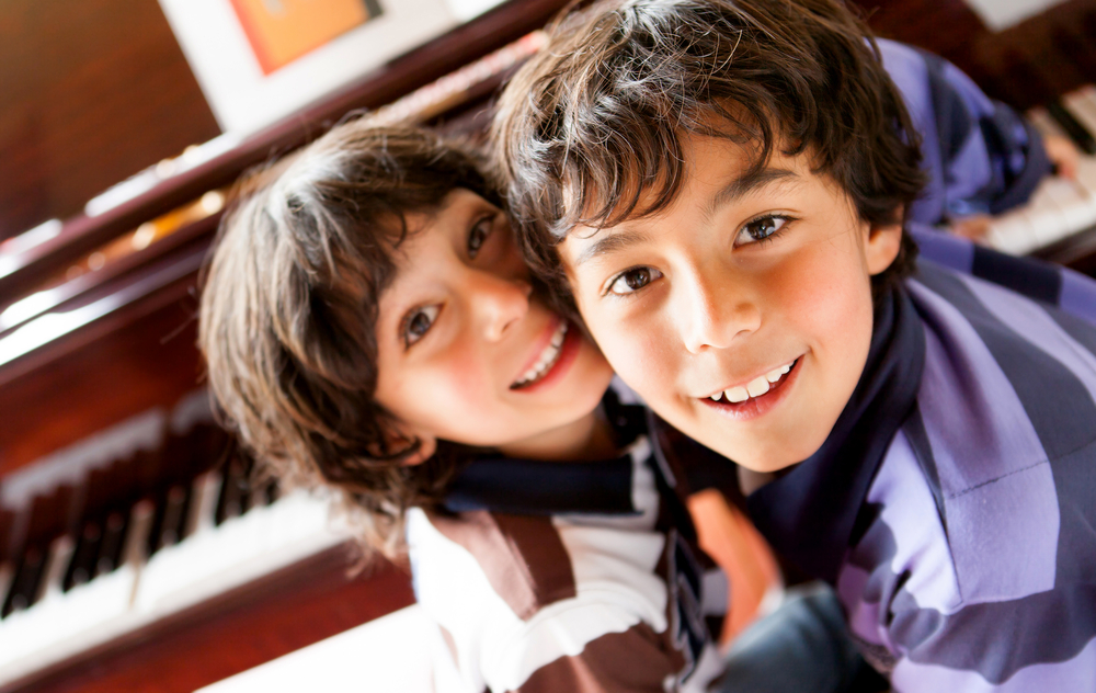 Boys playing music on a piano at home