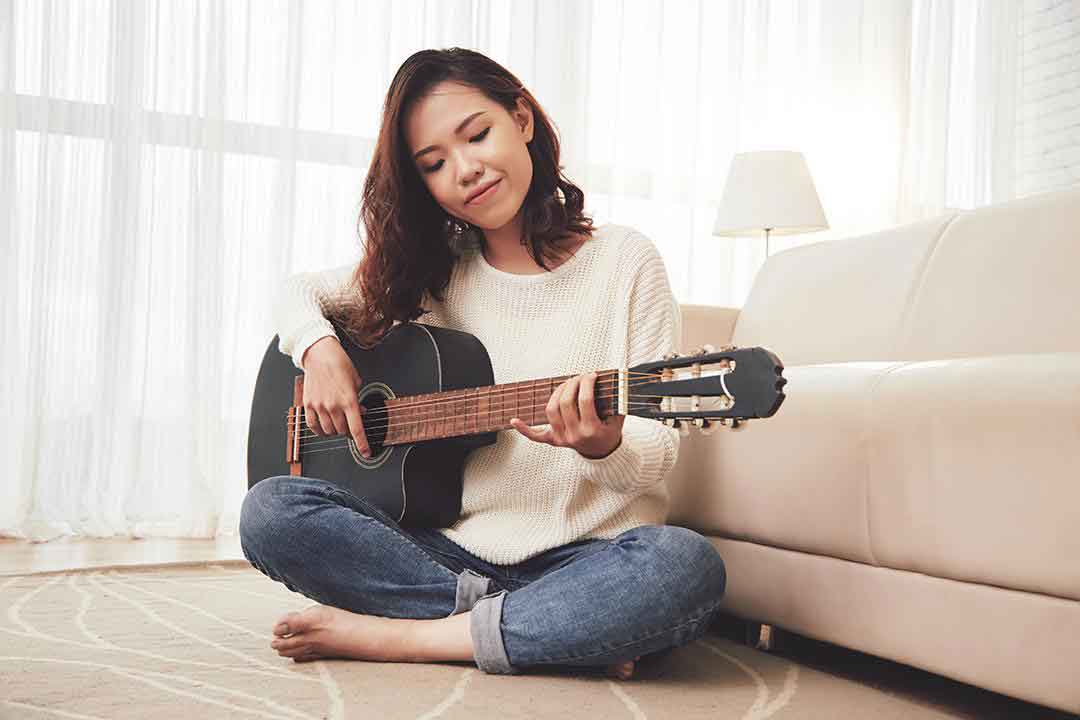 Femme-qui-joue-de-la-guitare-assise-par-terre.PH
