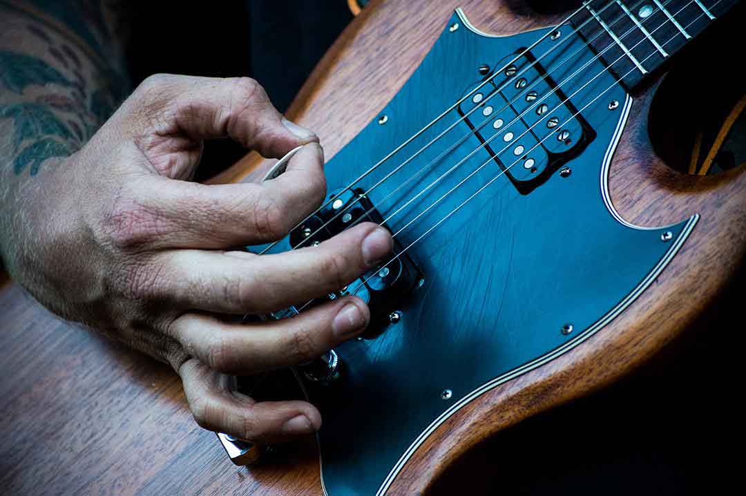 Focus-sur-une-main-qui-gratte-des-cordes-de-guitare.PH