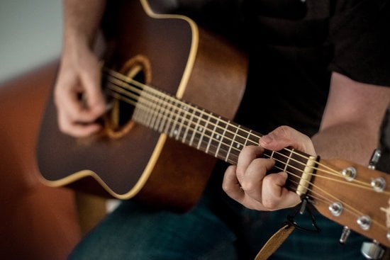 Homme qui joue de la guitare en faisant un accord de do