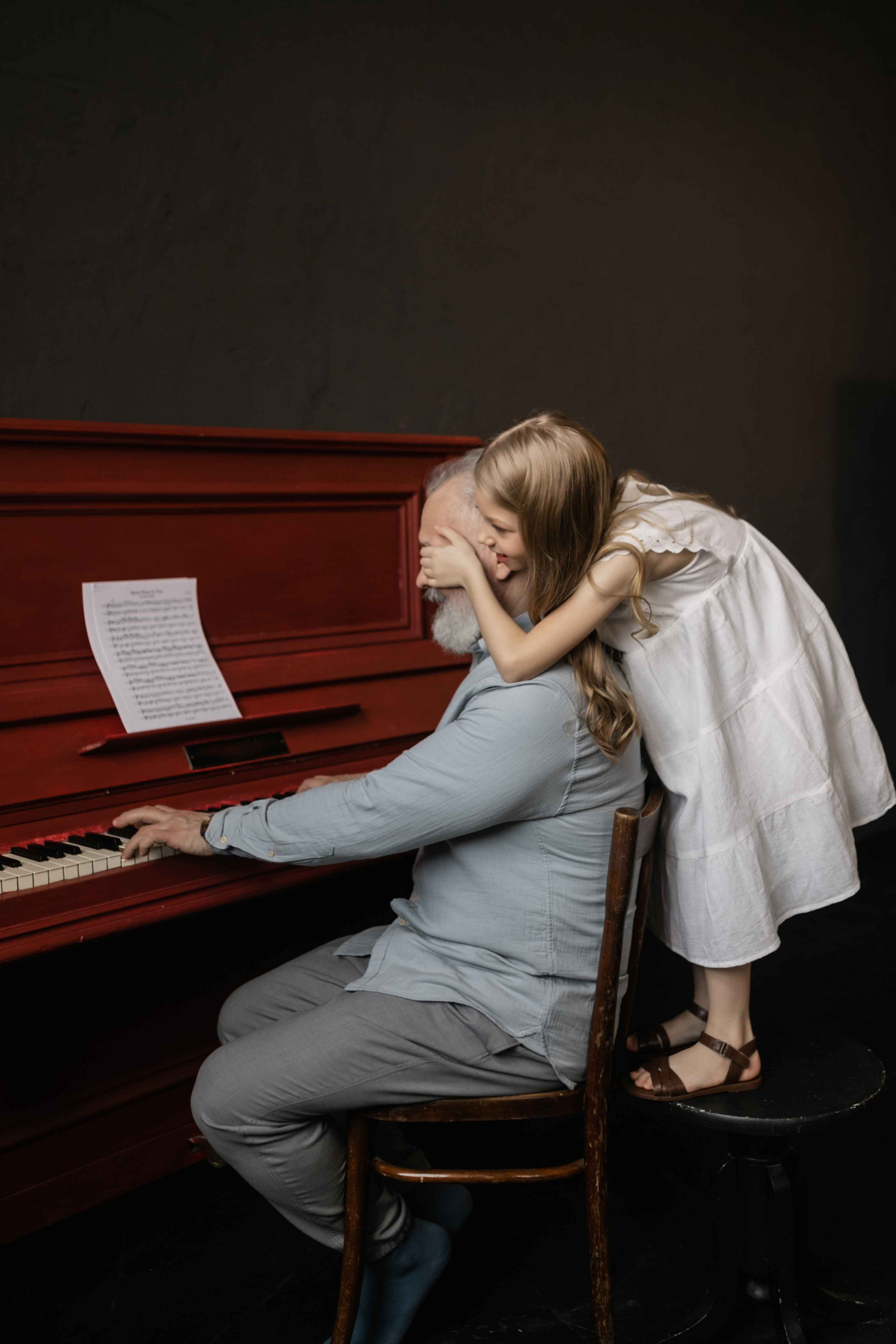 Petite fille qui cache les yeux d'un homme âgé pendant qu'il joue du piano. 