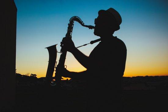 Photo d’un saxophoniste qui joue devant un coucher de soleil.