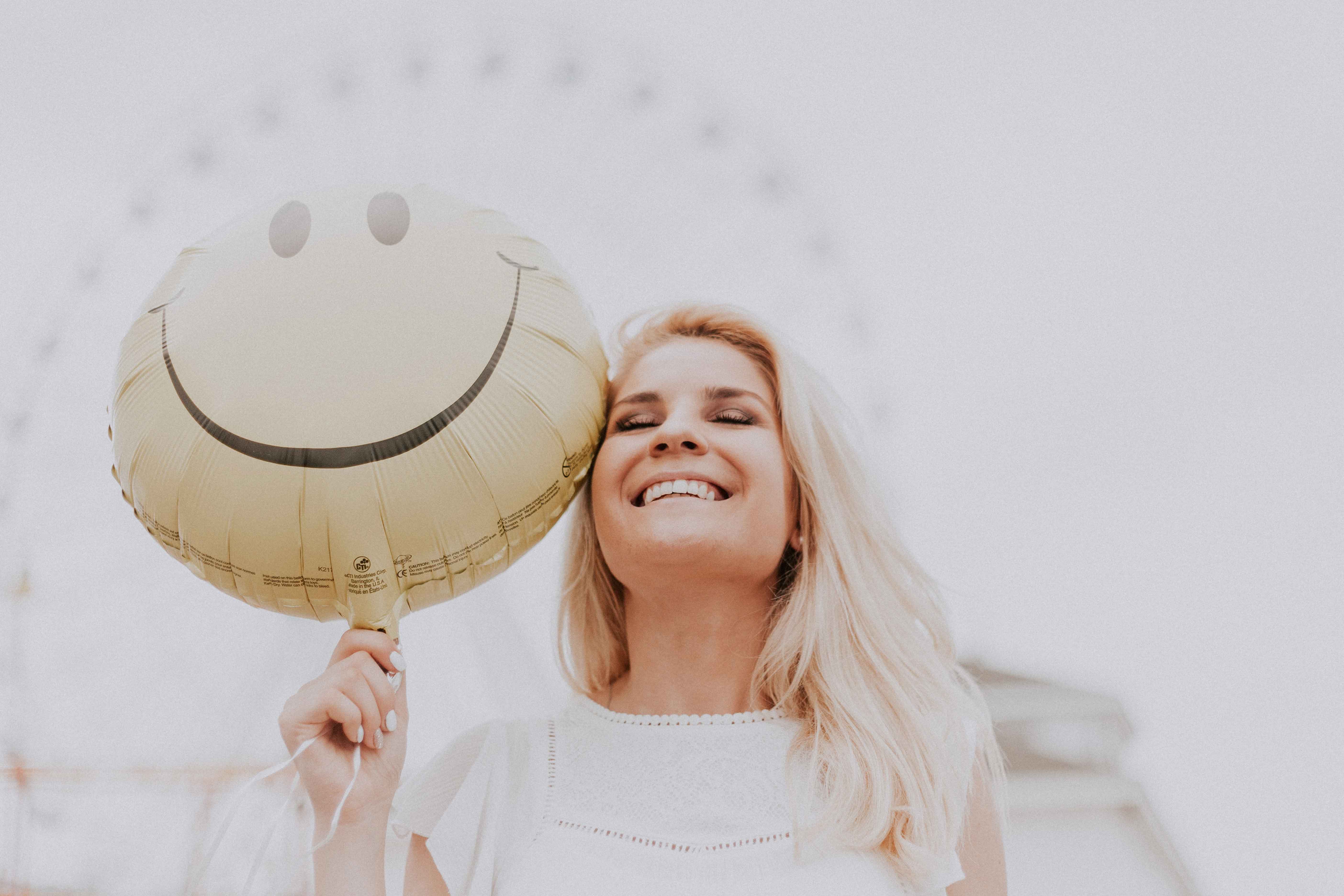 Femme heureuse avec un ballon smiley qui sourit - Quand rire et musique s'emmêlent