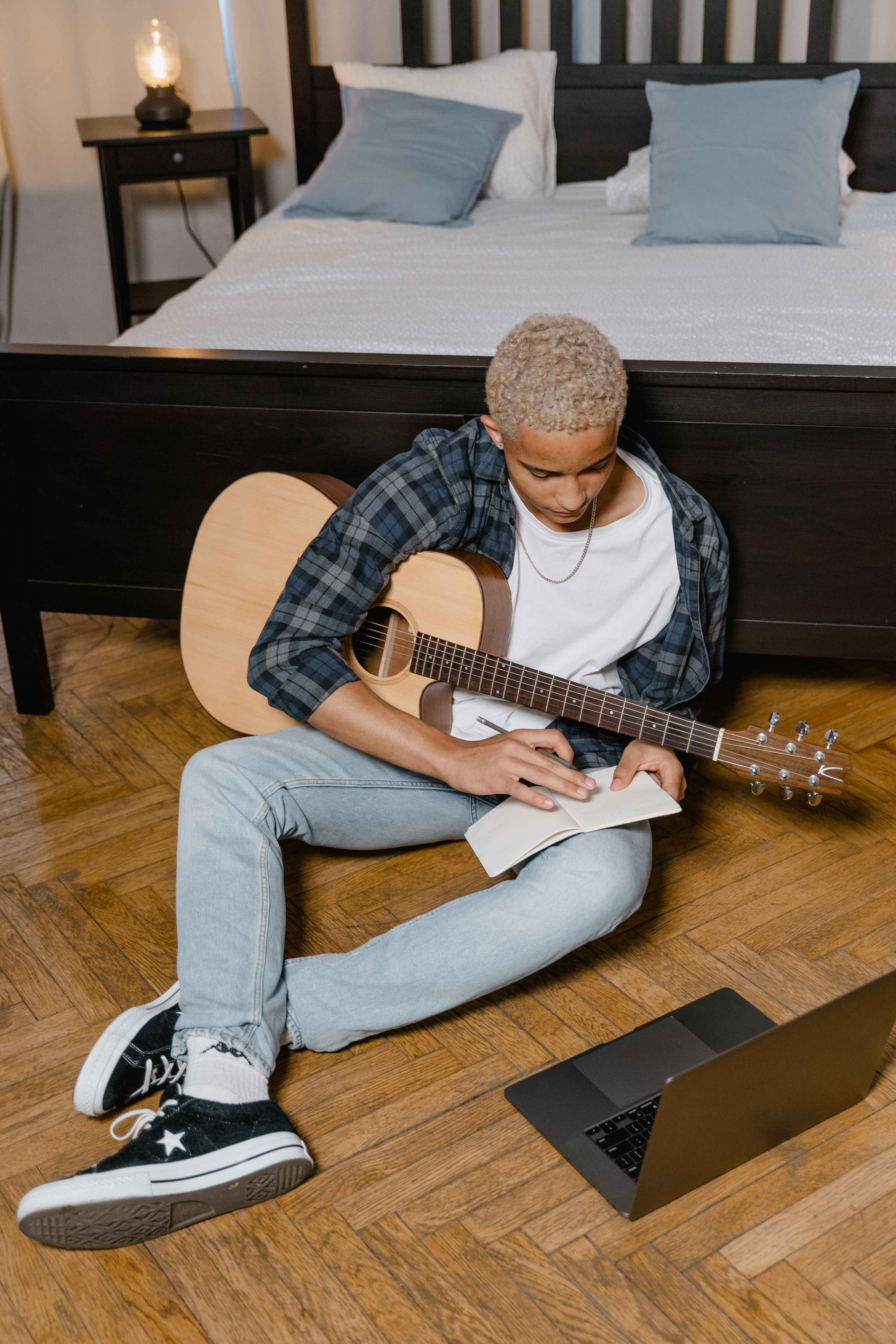 Homme avec une guitare assis notant les erreurs à éviter à la guitare